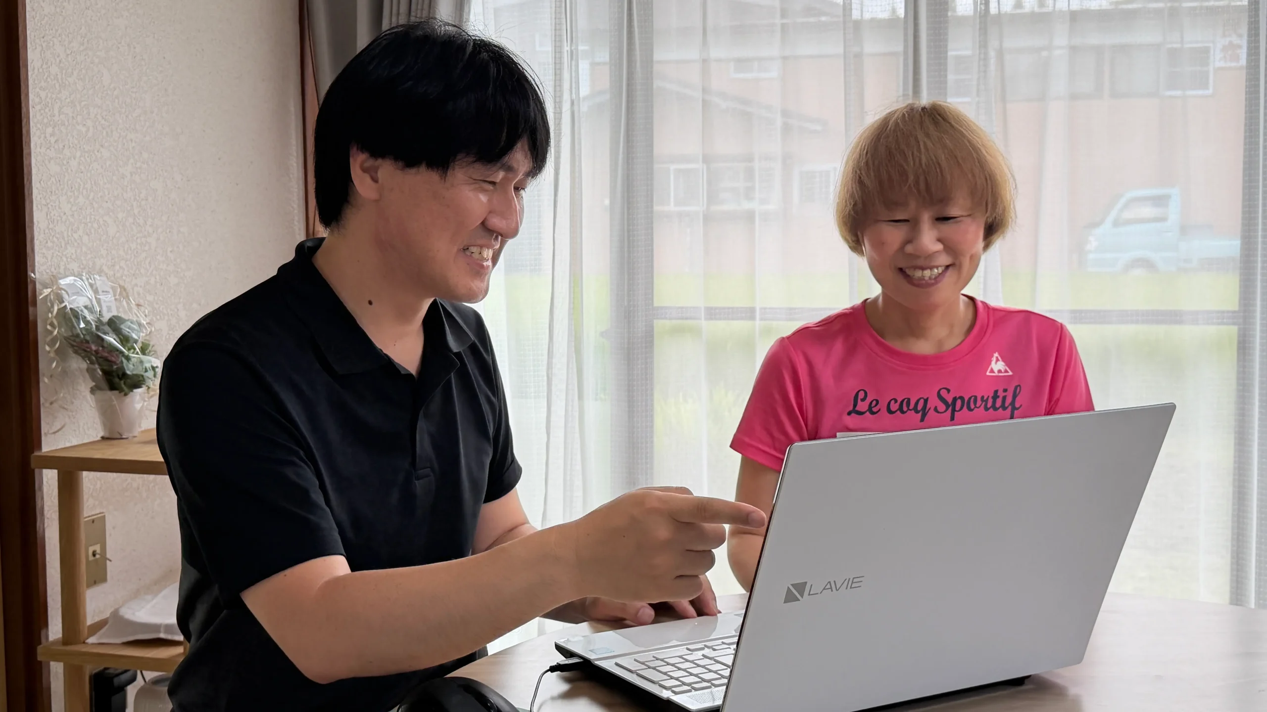ノートパソコンを見ながら利用者をサポートする大澤代表